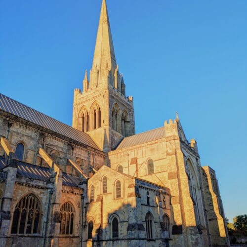 Chichester Cathedral. The warm yellow stone against a blue sky as the sun hits the spire.