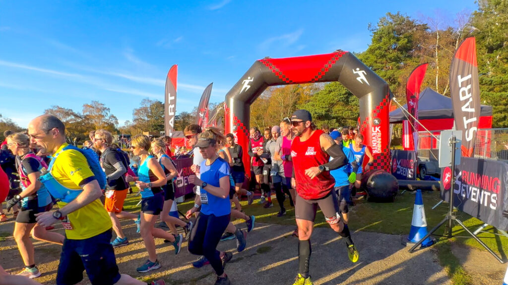 A crowd of runners pass under an inflatable start line