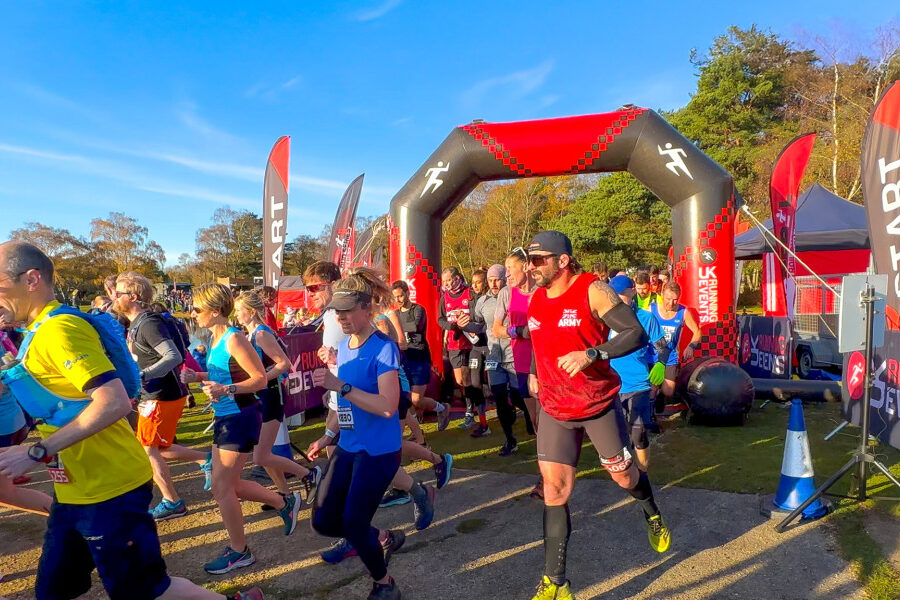 A crowd of runners pass under an inflatable start line